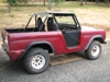 1968 Ford Bronco - A red 1968 Ford Bronco is parked outdoors, showing its open doors and removable top.