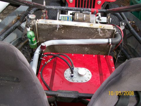 1984 Ford Bronco - This custom off-road vehicle features a prominent red fuel tank and radiator, with a visible license plate and Supermotors watermark.