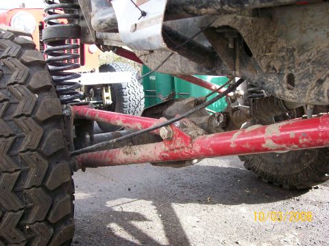1984 Ford Bronco - This photo shows the undercarriage and suspension of a modified off-road vehicle, with another vehicle in the background.