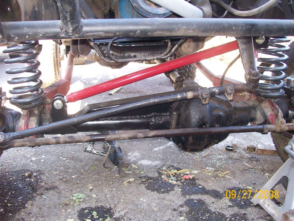 Close-up of a modified front axle with red shocks and heavy-duty suspension components