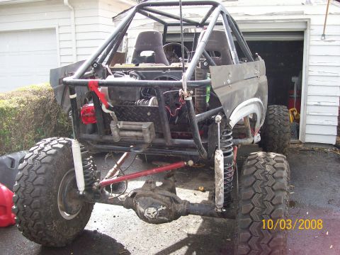 1984 Ford Bronco - This heavily modified off-road vehicle features a prominent roll cage and oversized tires, suggesting it is built for extreme terrain.