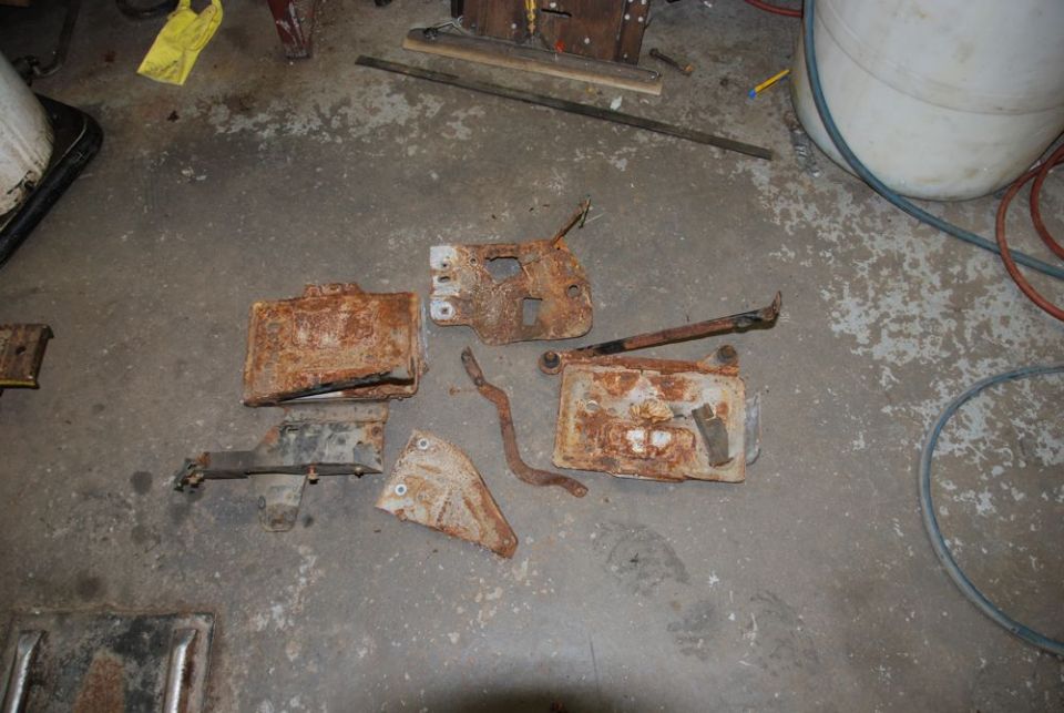 Several heavily rusted metal brackets and plates scattered on a concrete floor