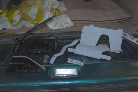 1996 Ford Bronco - Dual battery tray and associated mounting hardware are arranged on the bed of a teal vehicle.