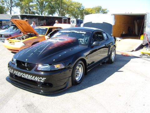 2007 Ford Mustang - A black Ford Mustang drag car is parked outside a trailer, with another car visible in the background.