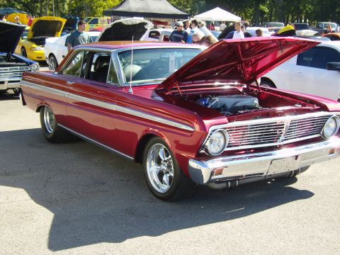 2007 Ford Mustang - A classic red Ford Falcon coupe is displayed with its hood open at an outdoor car show.