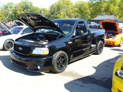 2007 Ford Mustang - Black 2000 Ford F-150 SVT Lightning pickup truck at a car show with other vehicles.