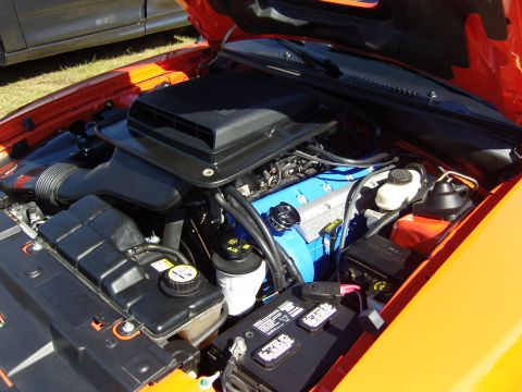 2007 Ford Mustang - Close-up of an engine bay, a prominent black air intake and blue valve covers with 'POWERED BY FORD' lettering.