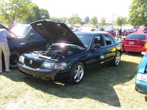 2007 Ford Mustang - A black sedan, possibly a Mercury Grand Marquis, is displayed with its hood open at an outdoor car show.