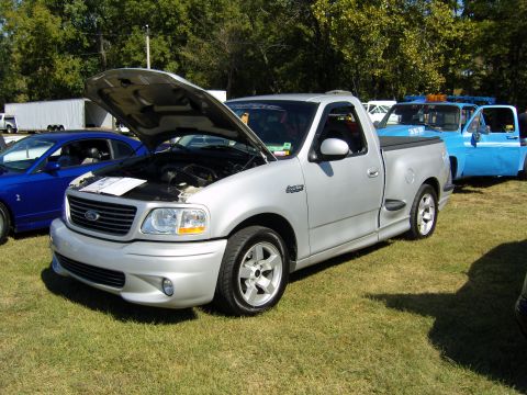 2007 Ford Mustang - Silver Ford F-150 SVT Lightning pickup truck, hood open, parked outdoors with other vehicles nearby.