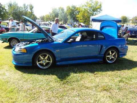 2007 Ford Mustang - A blue Ford Mustang GT is displayed with its hood and trunk open at a car show.