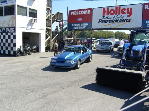 2007 Ford Mustang - A blue Ford Mustang, likely a 1993 model, drives onto the track at Beech Bend Raceway under a Holley Performance banner.