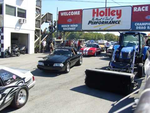 2007 Ford Mustang - A black fox body Mustang is seen at Beech Bend Raceway, with other vehicles and a tractor present.