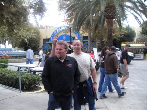 1990 Ford Bronco - Two men pose for a photo in front of a building with palm trees and other people around.