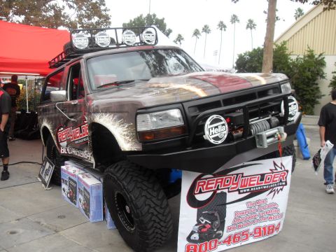 1990 Ford Bronco - This heavily modified SUV features custom paint, a roof rack with lights, a winch, and large off-road tires, suggesting a build from the ea…