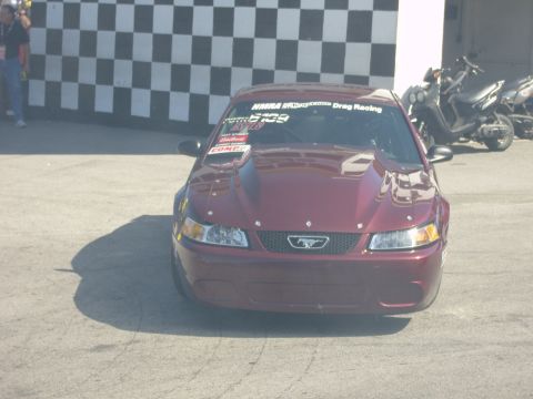 2007 Ford Mustang - This red Mustang features a prominent hood scoop and racing decals, suggesting it is prepared for track use.