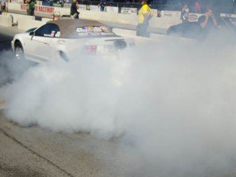2007 Ford Mustang - A white convertible performs a burnout, creating a large cloud of smoke on the drag strip.
