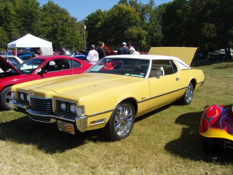2007 Ford Mustang - A yellow 1972 Ford Thunderbird coupe is parked on grass with its hood open, alongside other vehicles.