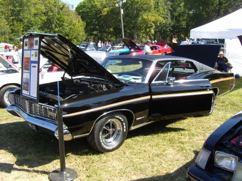 2007 Ford Mustang - Black 1969 Ford Torino GT displayed with its hood open at a car show event.