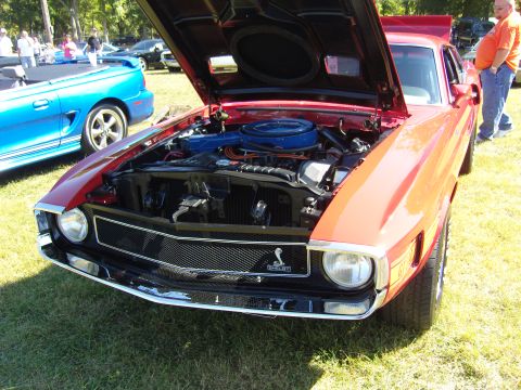 2007 Ford Mustang - A red 1969 Ford Mustang Mach 1 is parked on grass with its hood open, displaying the engine and a Cobra emblem.