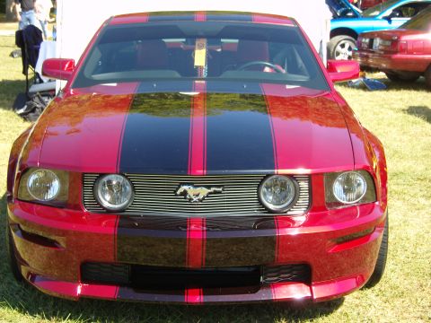 2007 Ford Mustang - Front view of a red 2007 Ford Mustang with black racing stripes parked on grass.