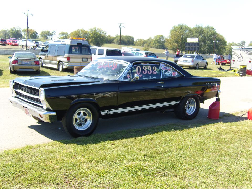 Black 1960s Ford Fairlane with racing numbers on the door parked on grass