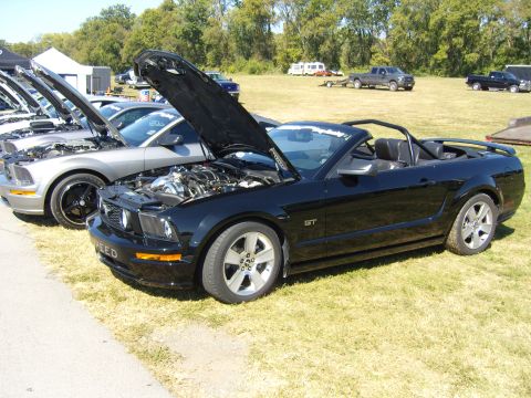 2007 Ford Mustang - A black 2007 Ford Mustang GT convertible is displayed with its hood open, alongside other vehicles.