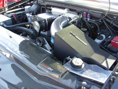 2007 Ford Mustang - Close-up of a modified engine bay a prominent supercharger and carbon fiber components.