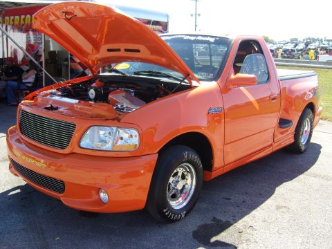 2007 Ford Mustang - This orange pickup truck is a Ford F-150 SVT Lightning, likely from the early 2000s.