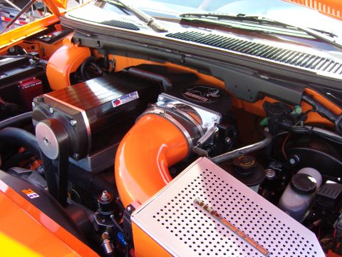 2007 Ford Mustang - Close-up view of a modified engine bay a prominent supercharger and orange intake piping.