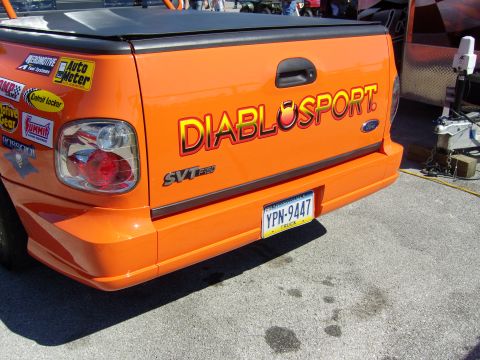 2007 Ford Mustang - Orange Ford SVT F-150 Lightning pickup truck features DiabloSport graphics and numerous racing decals on its tailgate.