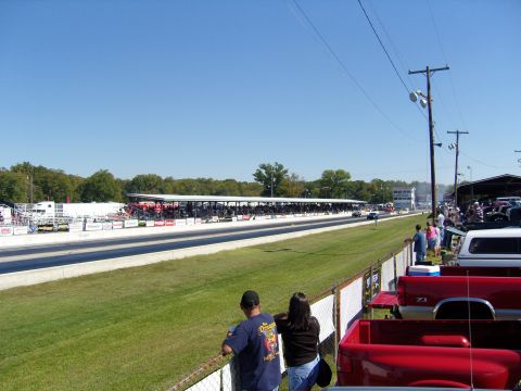 2007 Ford Mustang - Spectators watch a drag race from the sidelines, with numerous trucks parked in the background.