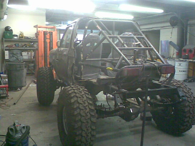 1984 Ford Bronco II with custom roll cage and off-road tires in a garage.