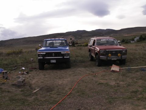 1977 Ford F-250 - A blue 1970s Ford F-series pickup truck is parked in a grassy field next to a red Ford Bronco. Both vehicles have "RMETC.COM" stickers on t…