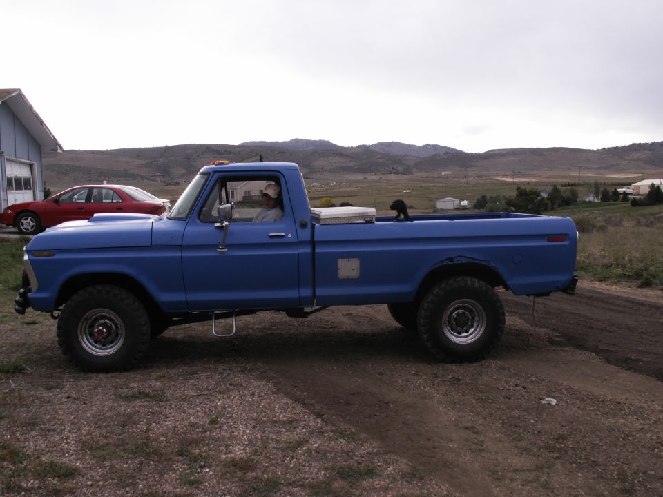 Blue 1977 Ford F-250 pickup truck parked on a dirt road.