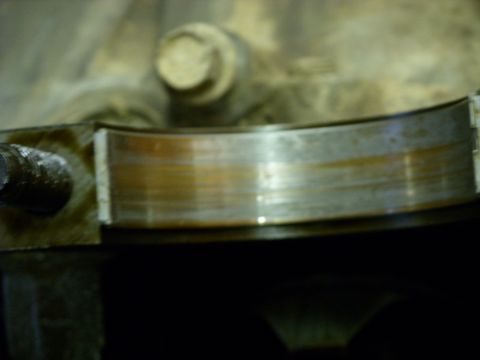 1988 Ford Bronco - Close-up of a worn engine bearing, showing signs of damage and discoloration.