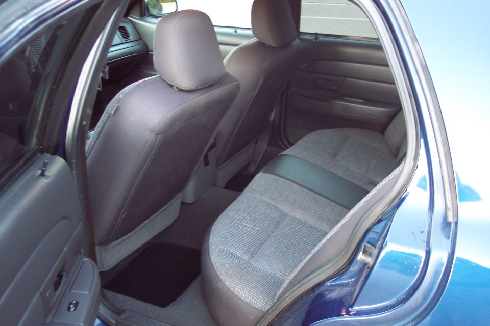 Gray cloth rear bench seat of a blue Ford Crown Victoria through the open door