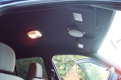 2001 Ford Crown Victoria - The interior ceiling of a vehicle, overhead lights and a dark fabric finish.