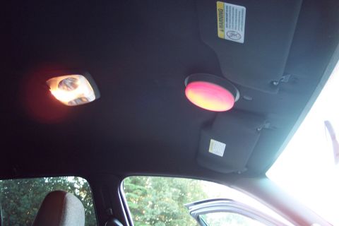 2001 Ford Crown Victoria - The interior ceiling of a vehicle shows two illuminated lights and folded sun visors.
