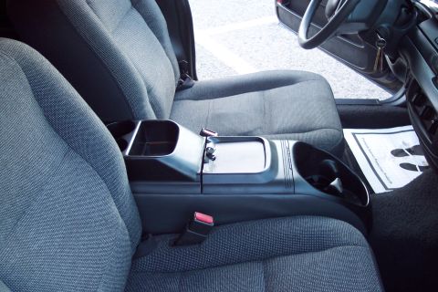 2001 Ford Crown Victoria - The interior of a 2001 Ford Crown Victoria features cloth seats and a center console with storage and cup holders. A document is visible on…