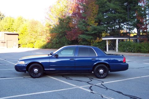2001 Ford Crown Victoria - Side profile of a blue 2001 Ford Crown Victoria sedan parked in an empty lot.
