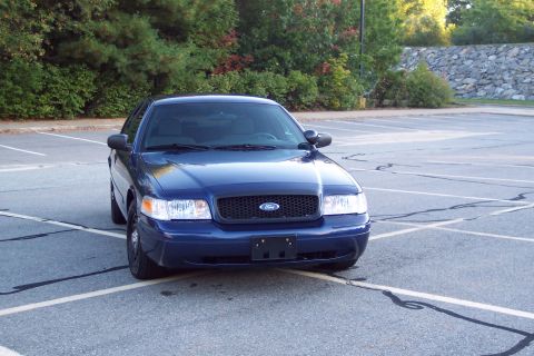 2001 Ford Crown Victoria - A blue 2001 Ford Crown Victoria is parked in an empty lot.