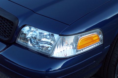 2001 Ford Crown Victoria - Close-up of the front corner of a blue 2001 Ford Crown Victoria, showing the headlight and grille.