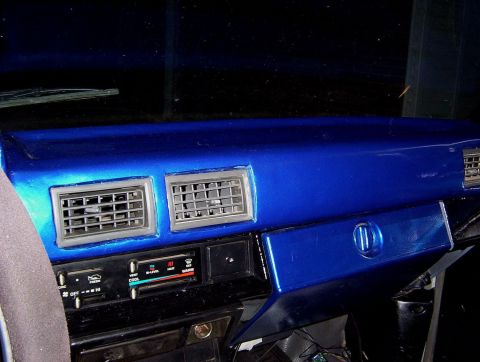 1986 Toyota Hilux - The interior of a vehicle shows a custom blue painted dashboard with air vents and climate controls.