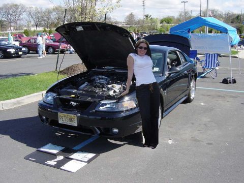 2001 Ford Mustang - A woman poses with her black 2001 Ford Mustang at an outdoor event.