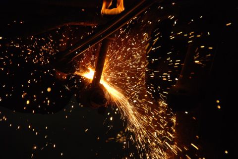1996 Ford Bronco - A close-up view of metal being cut, creating a shower of bright orange sparks against a dark, indistinct background.