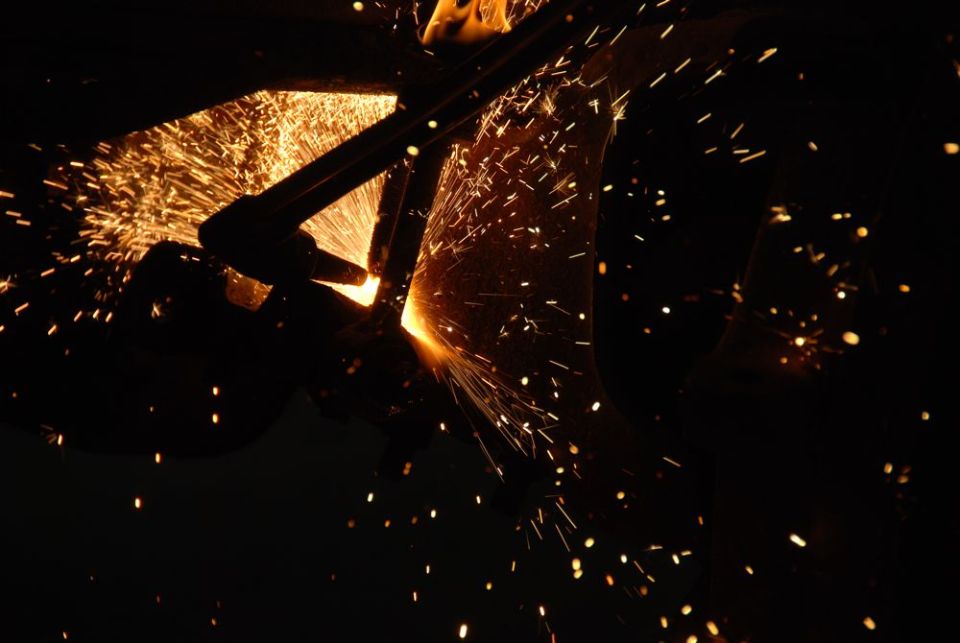Close-up of a torch cutting metal, creating a shower of bright orange sparks against a dark background