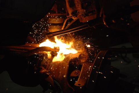 1996 Ford Bronco - A close-up shot shows a torch cutting into a metal component, with many sparks flying.