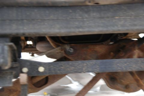 1996 Ford Bronco - Close-up view of the undercarriage of a vehicle, revealing suspension parts and exhaust system.
