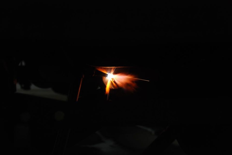 Welding torch creating sparks and flame in darkness