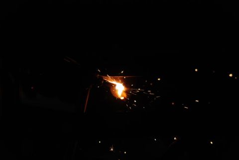1996 Ford Bronco - Bright sparks fly from a welding torch against a black background.